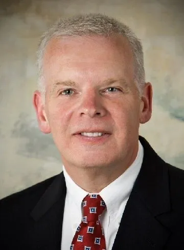 A man in suit and tie with white hair.