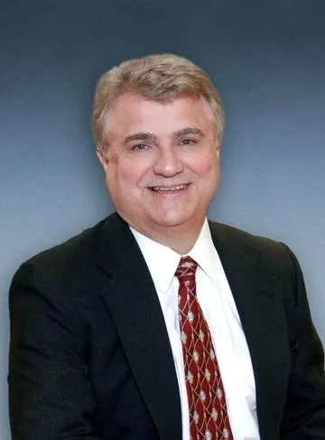 A man in a suit and tie smiling for the camera.