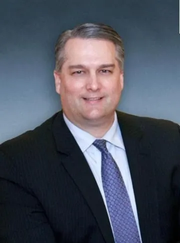 A man in suit and tie standing next to a wall.