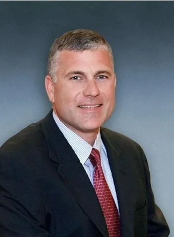 A man in suit and tie standing next to a wall.