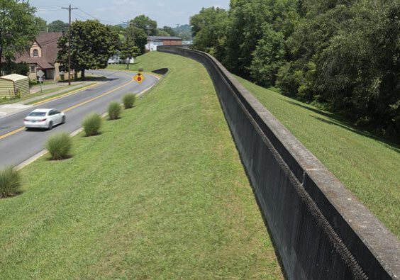 A long fence is on the side of a road.