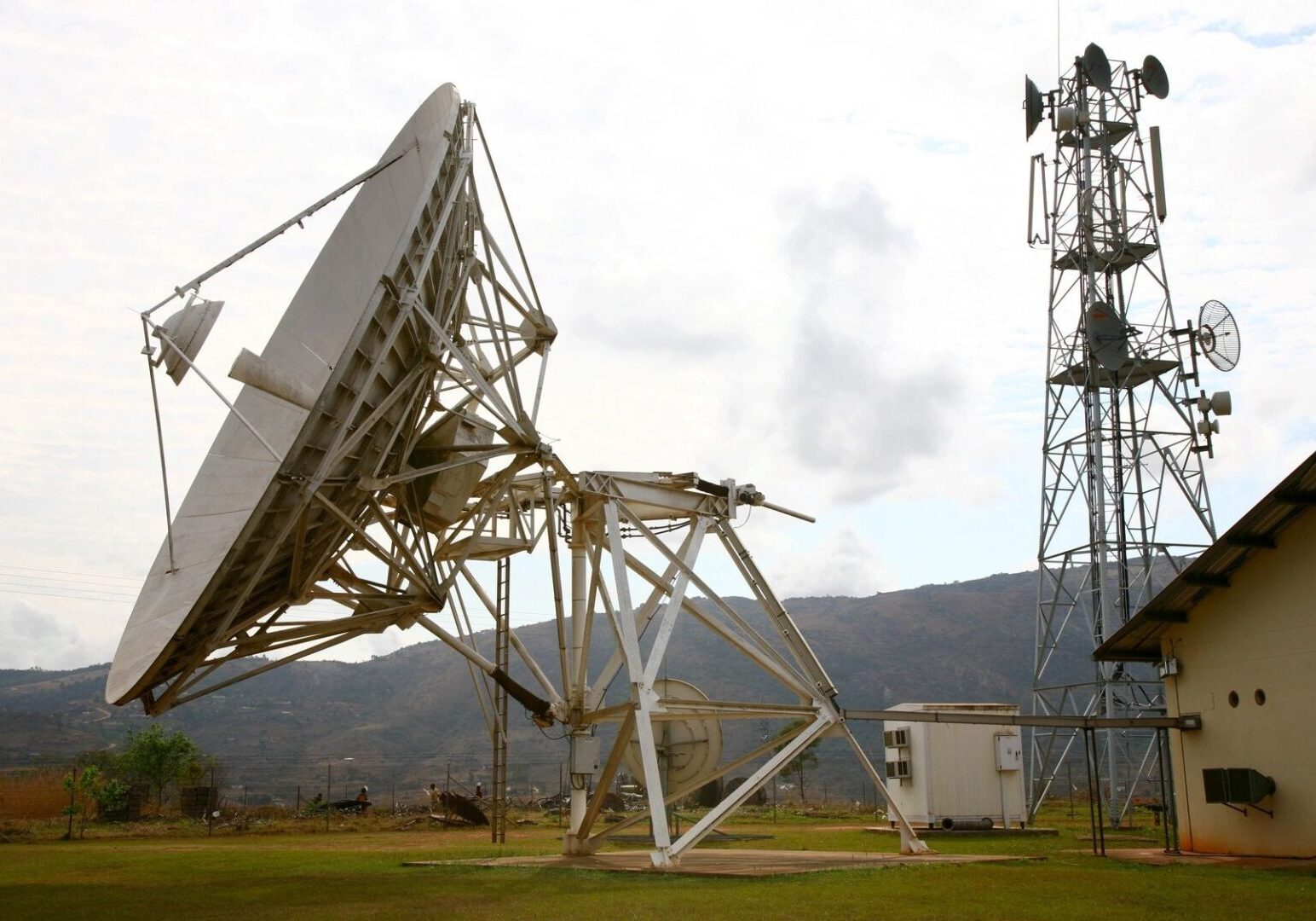 A large satellite dish sitting on top of a green field.